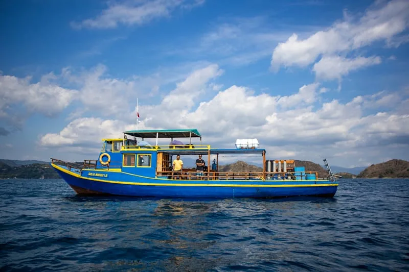 Bateau de plongée bleu et jaune avec des personnes à bord en mer