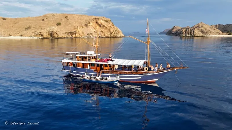 Bateau de plongée bleu navigue sur une mer calme avec des îles