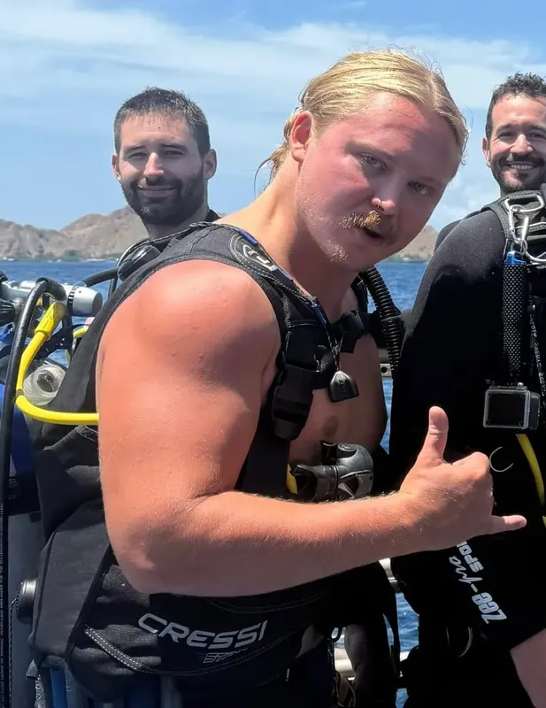 Plongeurs équipés sur un bateau, souriant et faisant un signe de validation