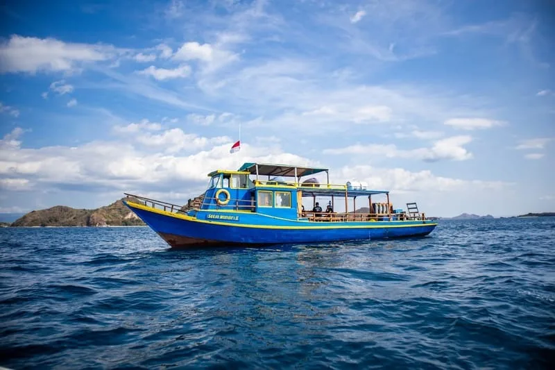Bateau bleu en mer avec des passagers et un ciel nuageux
