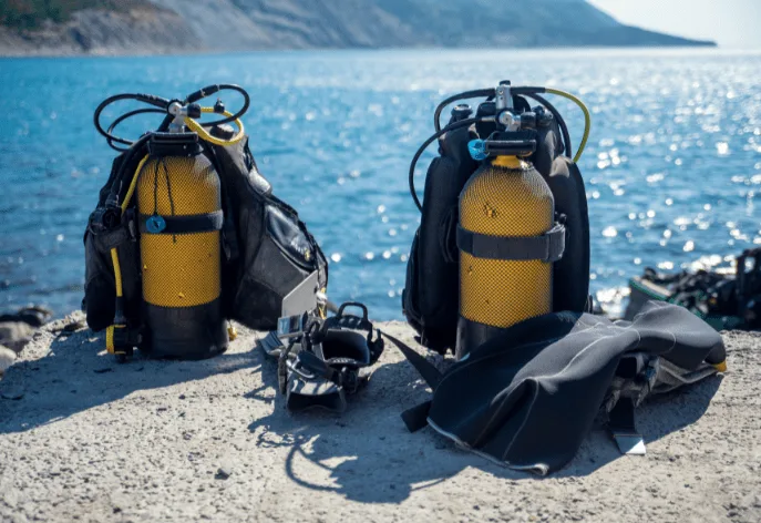 Equipement de plongée complet : bouteilles, détendeurs, gilet et palmes sur plage