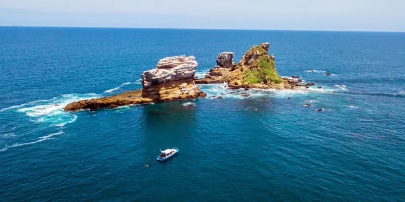 Île rocheuse au milieu de l'océan, avec un bateau de plongée
