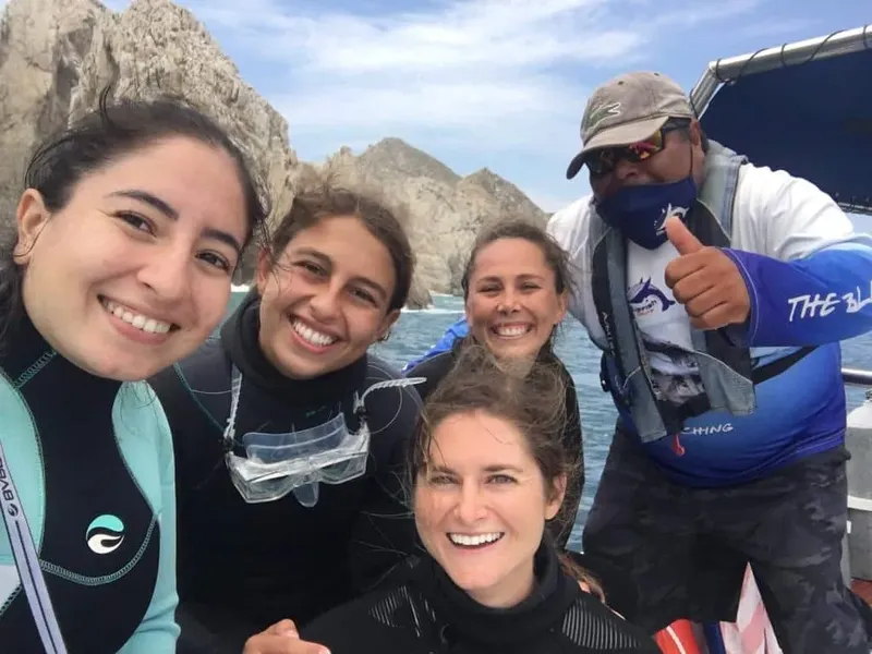 Groupe de personnes souriantes sur un bateau en mer, ciel bleu