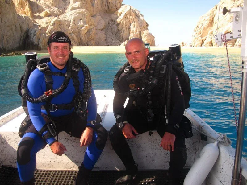 Deux plongeurs équipés sont assis sur un bateau en mer