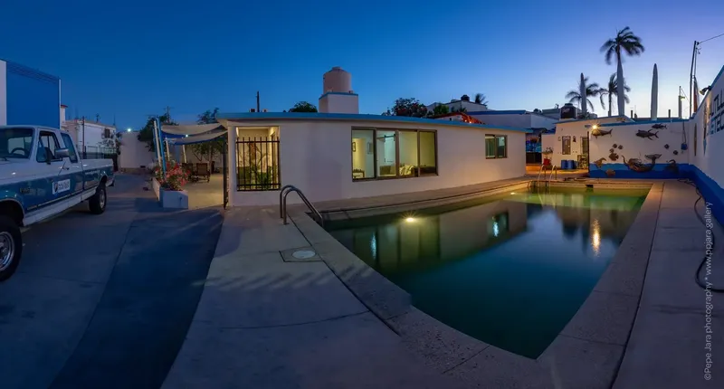 Bâtiment blanc avec piscine et parking, ciel bleu au coucher du soleil
