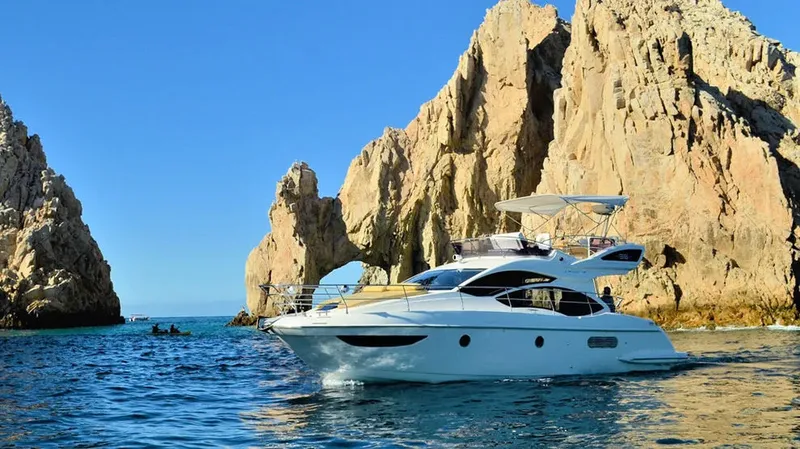 Grand yacht blanc navigue près de formations rocheuses et de plongeurs