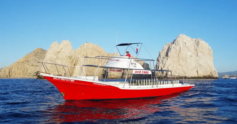Bateau de plongée rouge en mer avec des formations rocheuses en arrière-plan