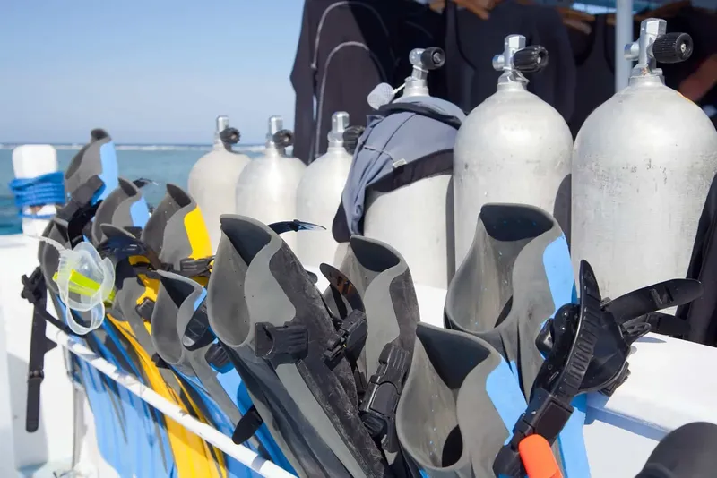 Bouteilles de plongée, palmes et masques alignés sur un bateau de plongée