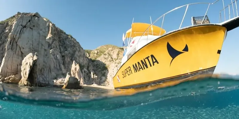 Bateau jaune et blanc à moitié immergé devant une falaise rocheuse