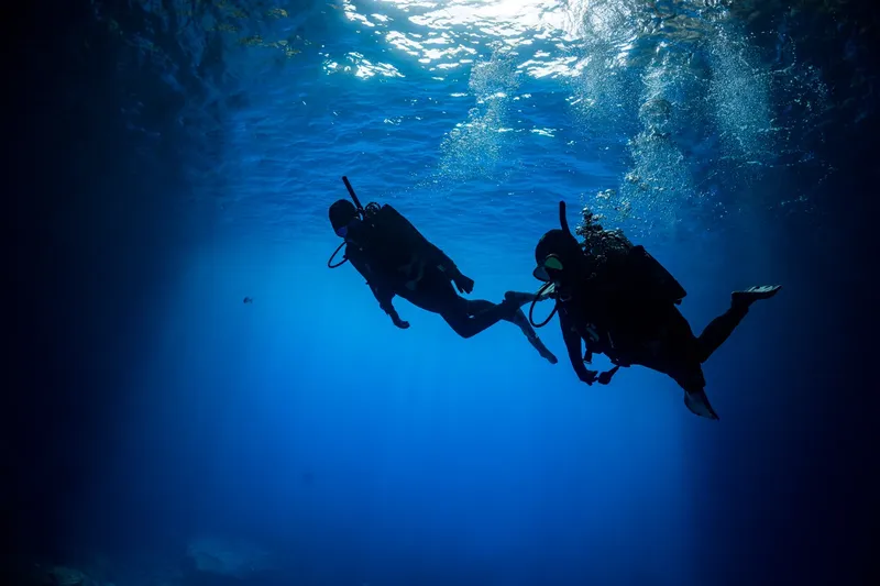 Deux plongeurs explorent les profondeurs bleues, silhouette humaine sous-marine