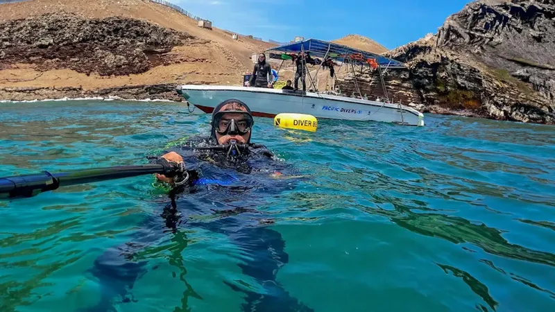 Plongeur en surface avec bateau et côte rocheuse en arrière-plan