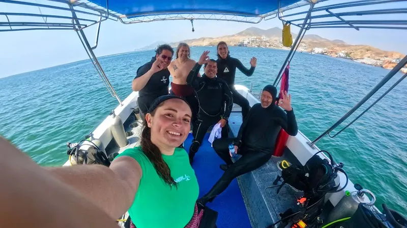 Groupe de plongeurs souriants sur un bateau en mer, équipement visible