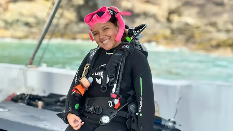 Plongeuse souriante en combinaison complète sur un bateau de plongée