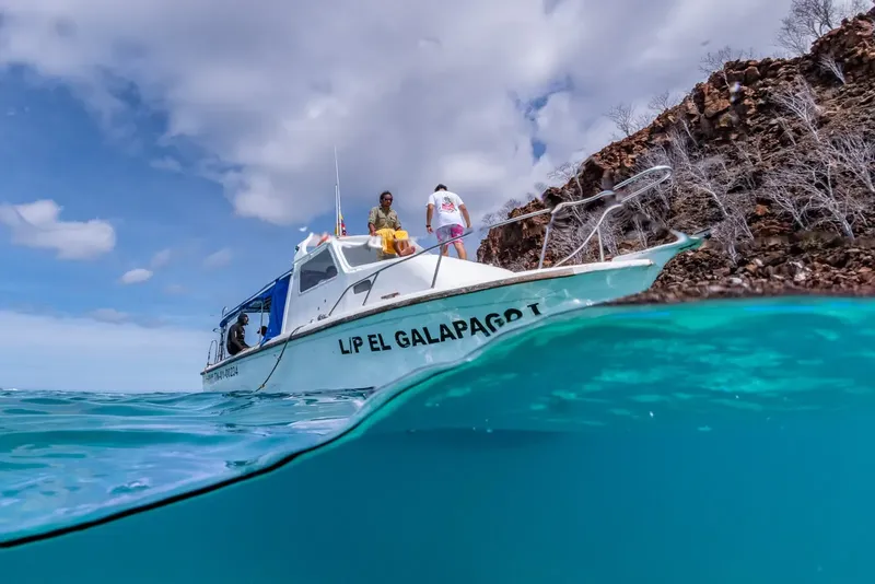 Bateau de plongée blanc et bleu sur l'eau turquoise avec des personnes