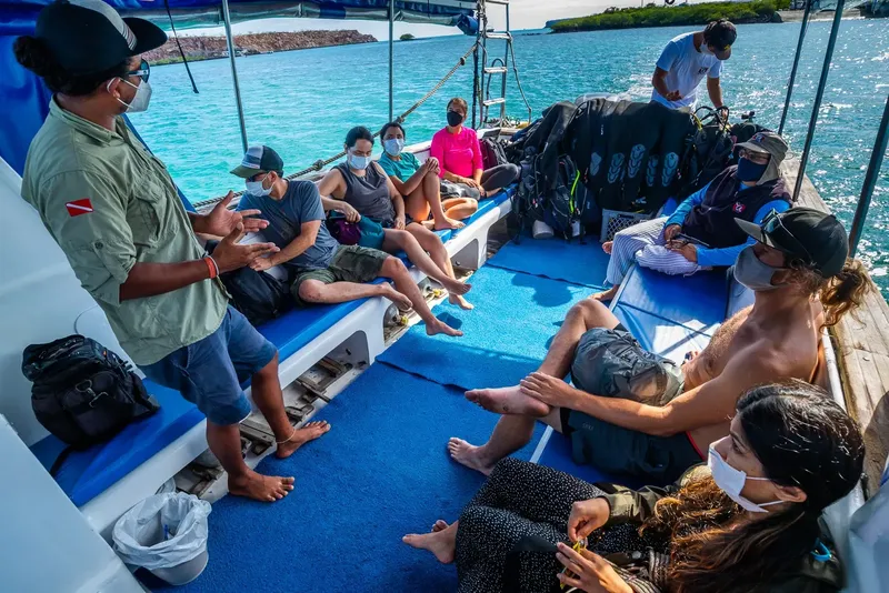 Groupe de plongeurs masqués discutent à bord d'un bateau en mer