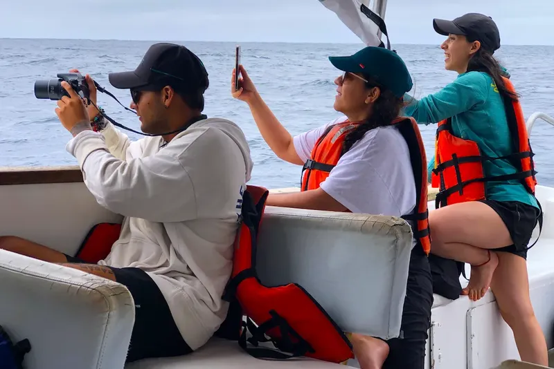 Trois personnes sur un bateau, regardent le paysage ou prennent des photos