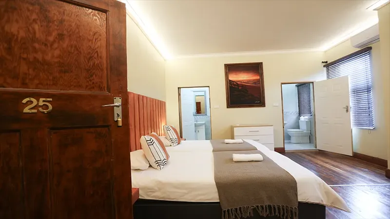 Chambre d'hôtel avec deux lits, salle de bain et décoration sobre