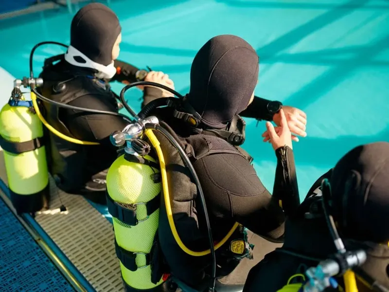 Plongeurs en préparation avec leur équipement complet au bord d'une piscine