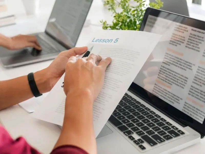 Personne tenant un stylo et lisant un document sur une table