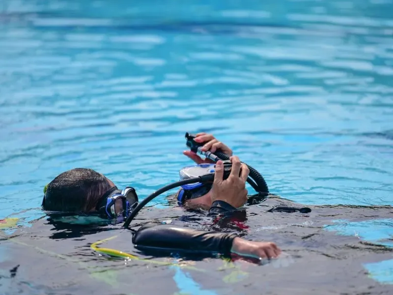 Plongeur en formation manipule son détendeur dans une piscine