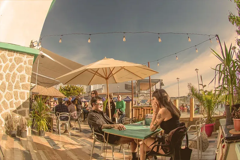 Terrasse ensoleillée avec tables, parasols et personnes assises