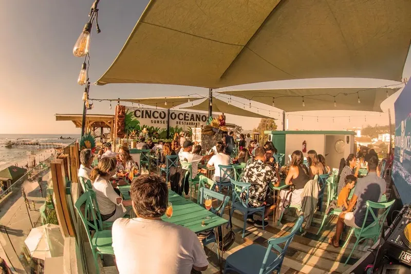 Terrasse de restaurant bondée avec vue sur la plage et le coucher de soleil