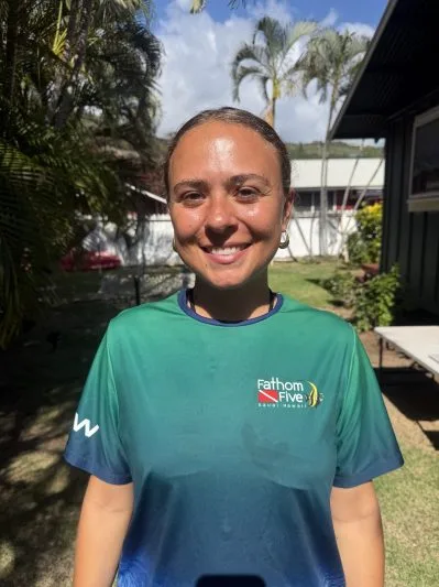 Femme souriante portant un t-shirt avec un logo de centre de plongée