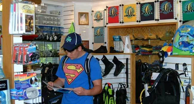 Un homme examine un catalogue dans un magasin de plongée bien garni