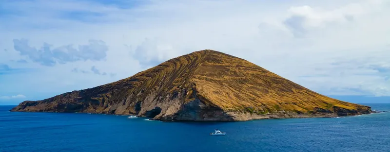 Vue d'une île volcanique rocheuse entourée d'une mer bleue et calme