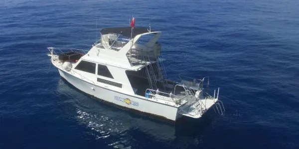 Bateau de plongée blanc sur une mer bleue calme et ensoleillée