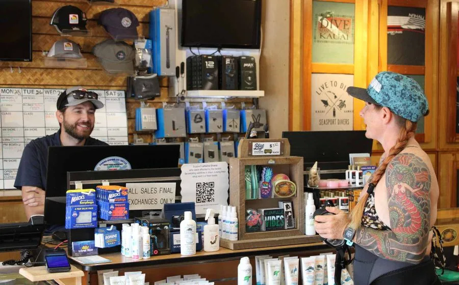 Deux employés derrière un comptoir de centre de plongée souriants
