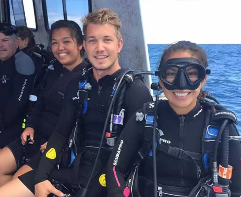 Plongeurs souriants équipés sur un bateau avant une immersion