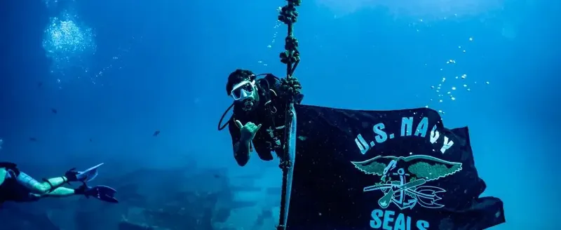 Plongeur tenant un drapeau U.S. Navy SEALs dans l'eau bleue
