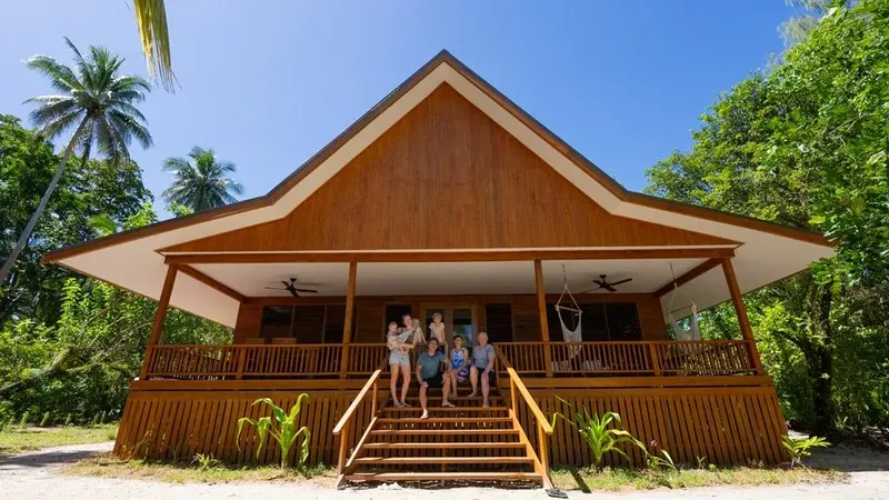 Groupe de personnes souriantes devant un bâtiment en bois tropical