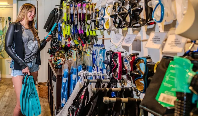 Jeune femme choisit son équipement de plongée dans un magasin
