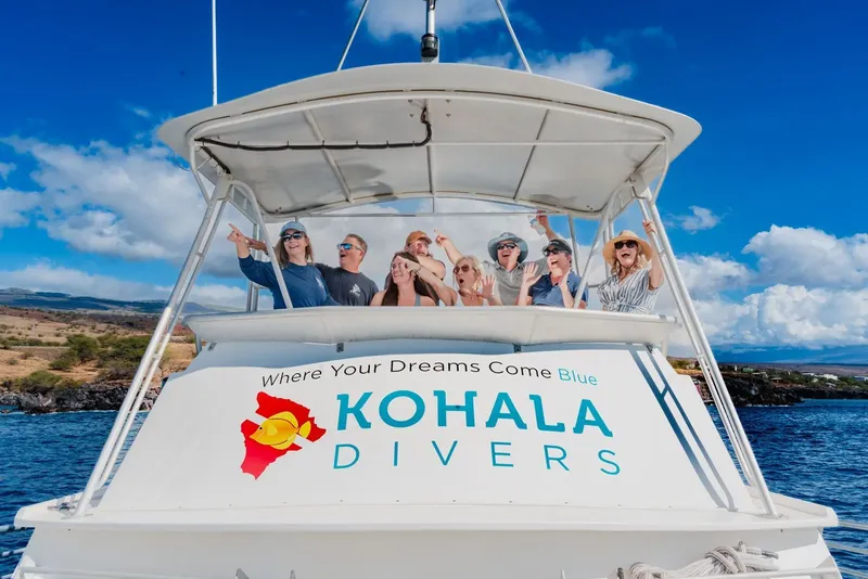 Groupe de personnes souriantes sur un bateau en mer, ciel bleu