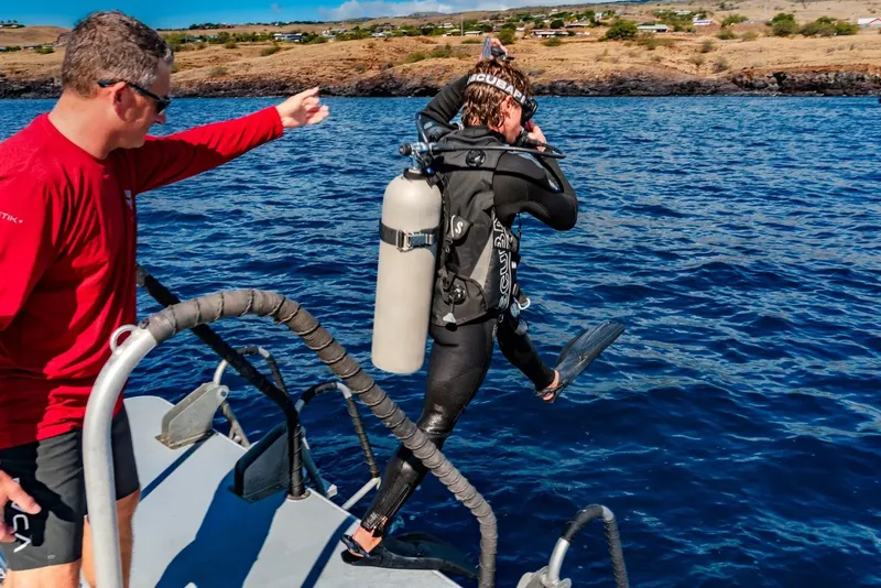 Plongeur s'équipant sur un bateau avec l'aide d'un instructeur