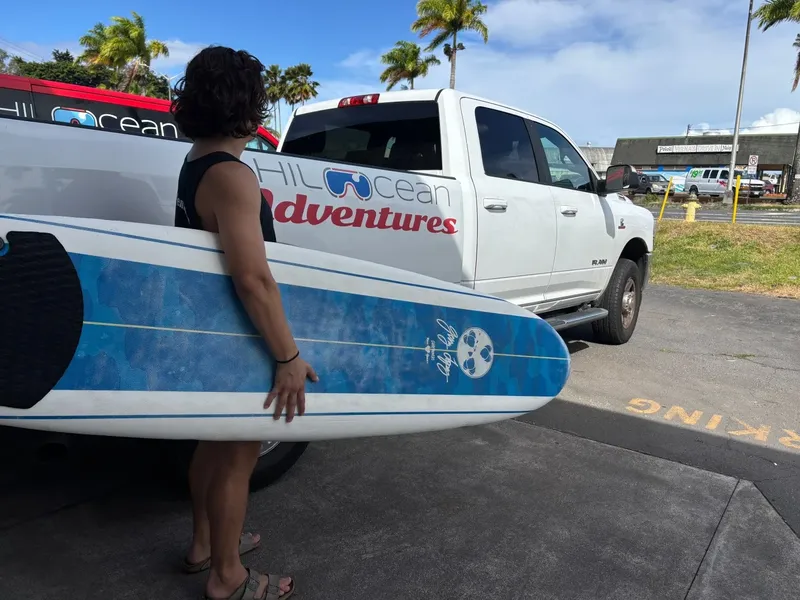 Femme tenant une planche de stand-up paddle près d'un pick-up blanc