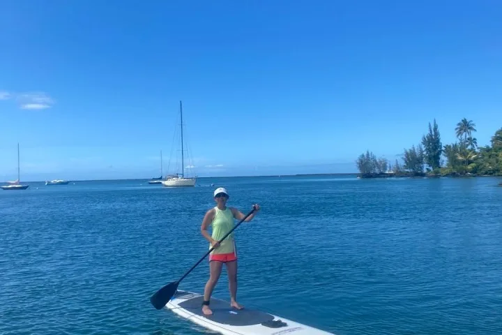 Femme debout sur une planche de paddle au milieu de la mer
