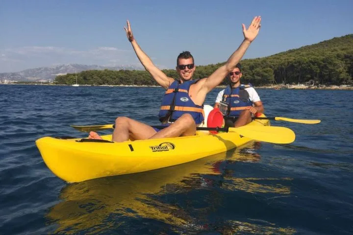 Deux hommes souriants en kayak jaune sur mer bleue