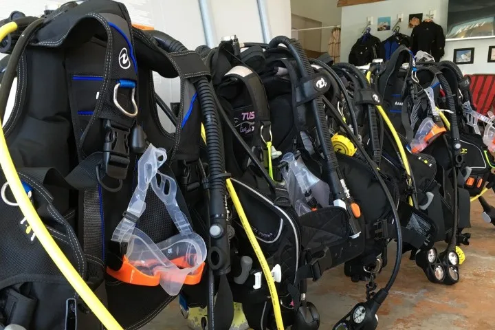Rangée d'équipements de plongée complets, gilets, détendeurs, bouteilles