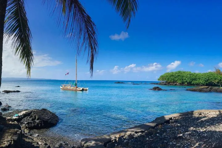 Voilier amarré dans une baie turquoise bordée de végétation luxuriante