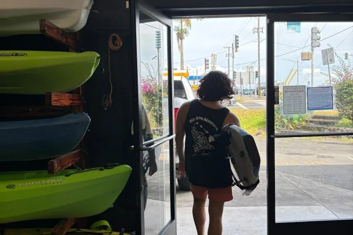Une personne sort d'un local avec du matériel de plongée sur l'épaule