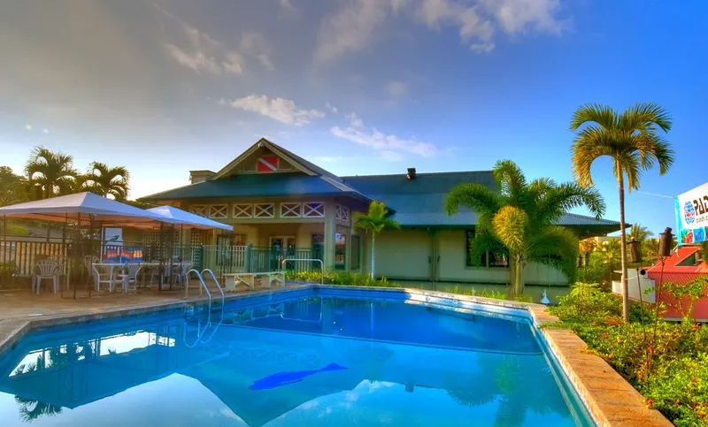 Bâtiment principal du centre de plongée avec piscine et végétation tropicale