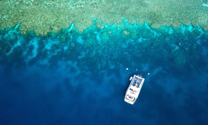 Catamaran en mer au dessus d'un récif corallien turquoise