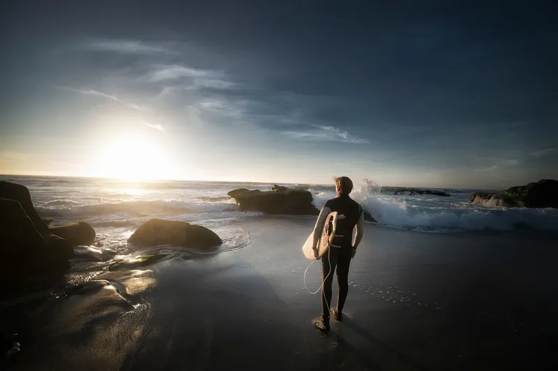 Silhouette d'une personne en combinaison de plongée marchant vers la mer