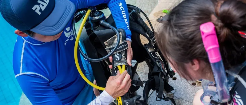 Un instructeur vérifie l'équipement d'une plongeuse avant une immersion