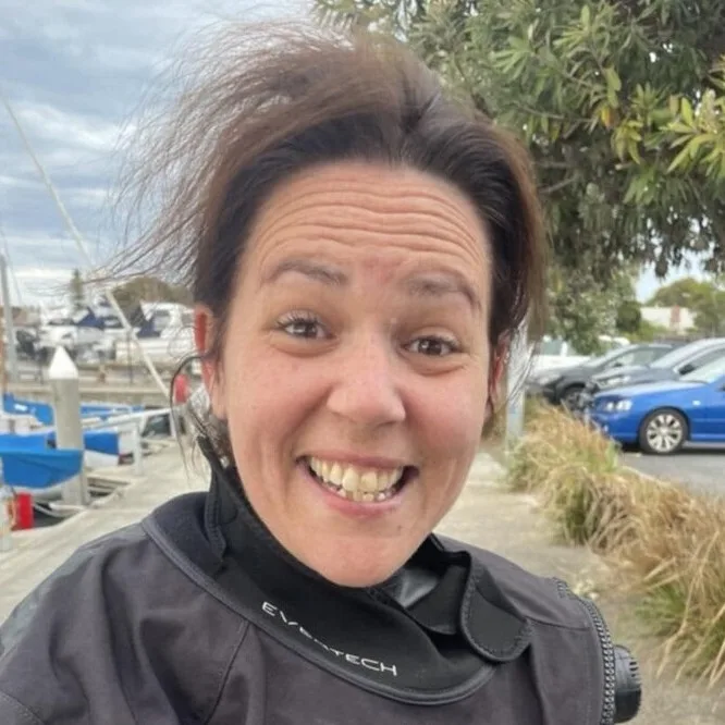 Femme souriante en combinaison de plongée près d'un port de plaisance