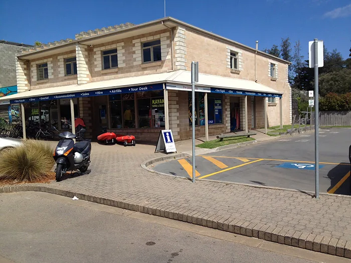 Façade d'un bâtiment avec des auvents, un scooter et une place de parking