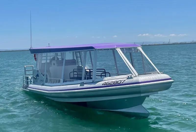 Bateau semi-rigide blanc et violet naviguant sur une mer turquoise calme